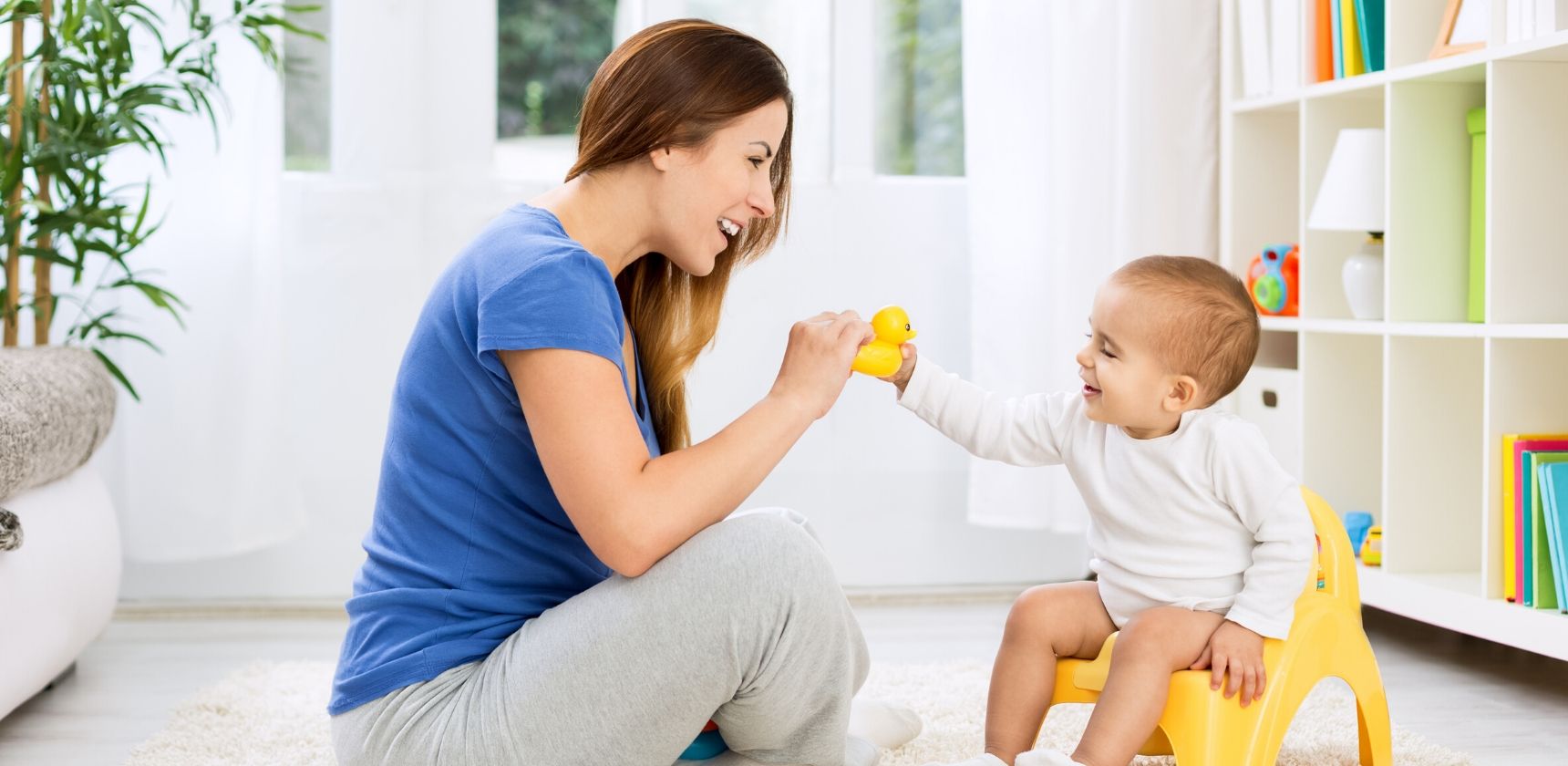 mom playing with toddler sitting on potty chair