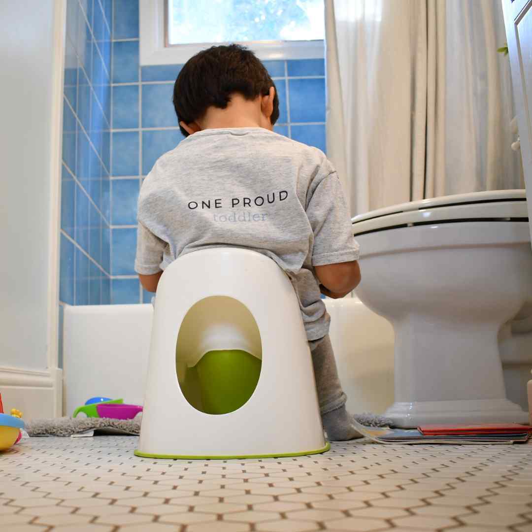 toddler sitting on potty chair reading book